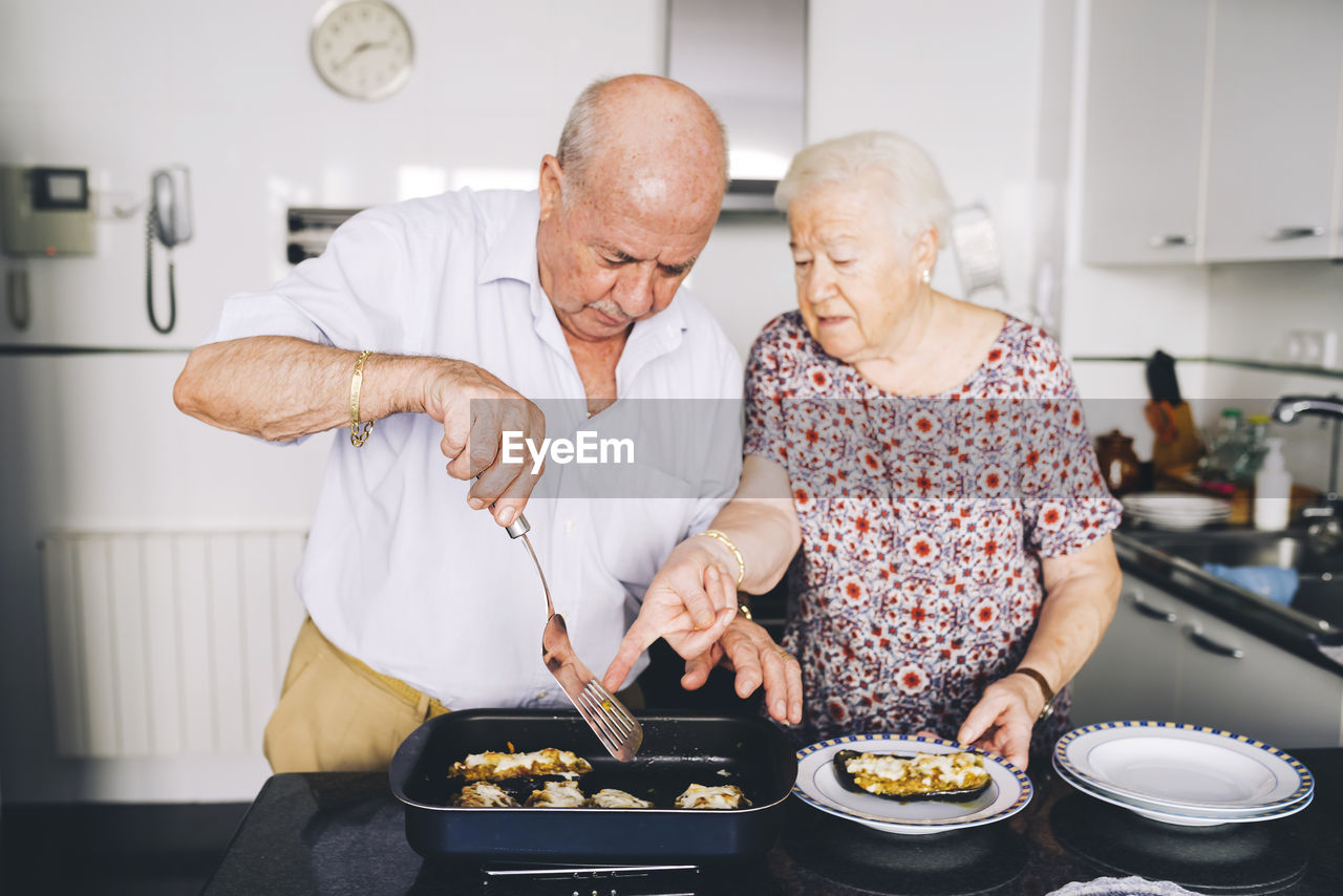 Senior couple serving stuffed eggplants in the kitchen