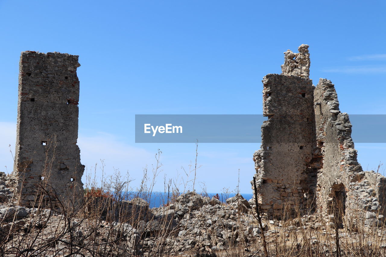 ruins, history, sky, architecture, the past, old ruin, built structure, nature, blue, castle, ancient history, ancient, rock, no people, tower, clear sky, building, travel destinations, ruined, old, landmark, building exterior, travel, abandoned, day, damaged, land, fort, outdoors, fortification, plant, low angle view, stone material, historic site, landscape, sunny, wall, medieval, scenics - nature, tourism, rundown