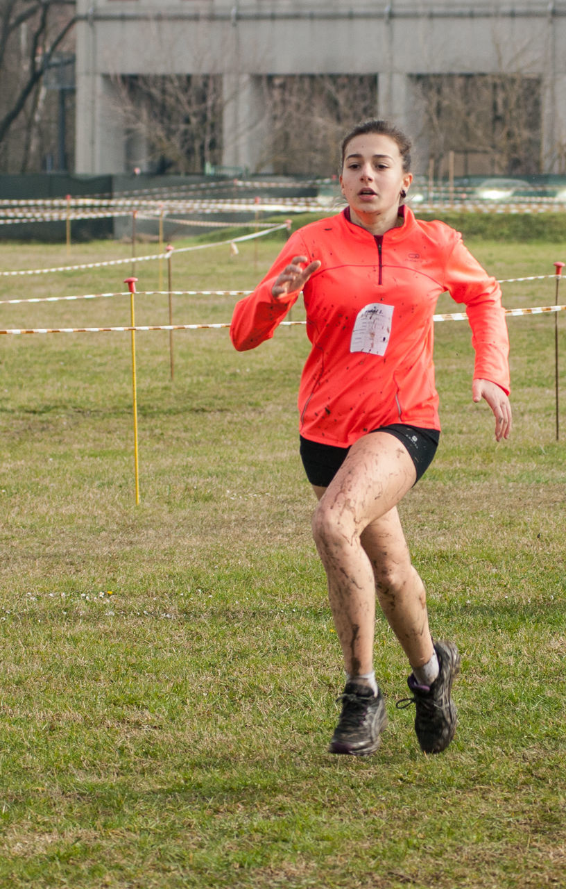 Young female athlete running on field