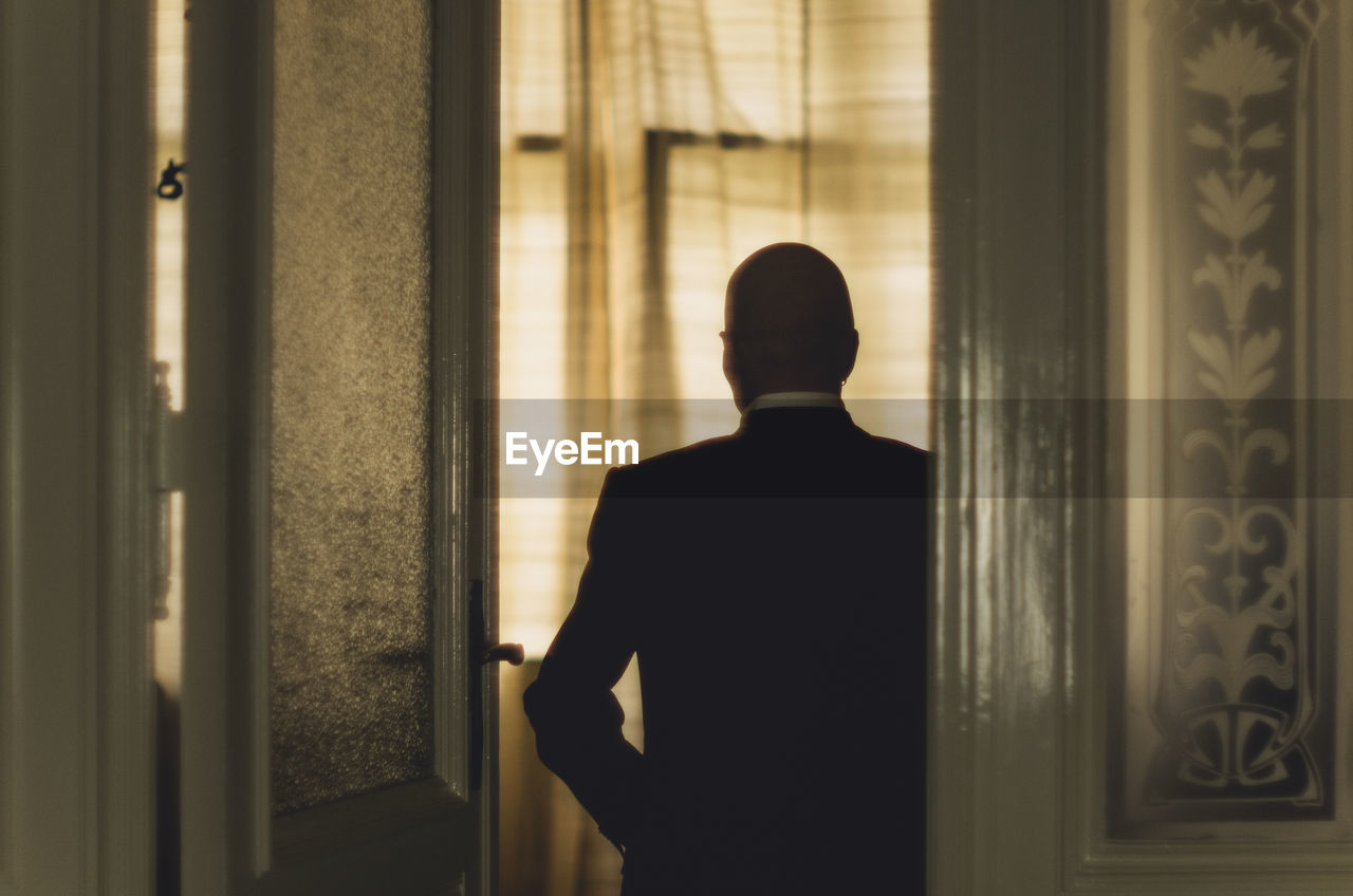 Rear view of businessman in suit standing by door