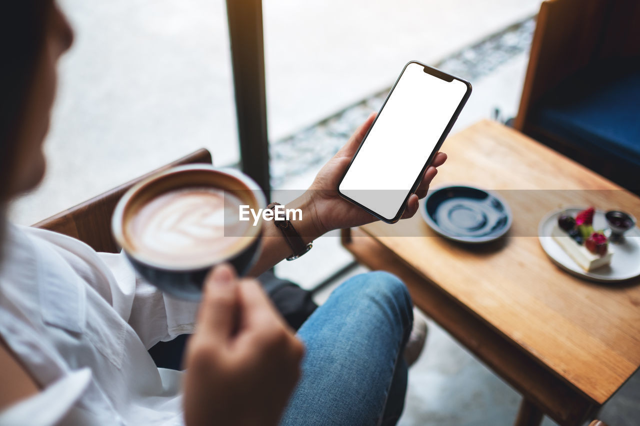 midsection of woman using mobile phone while sitting on table