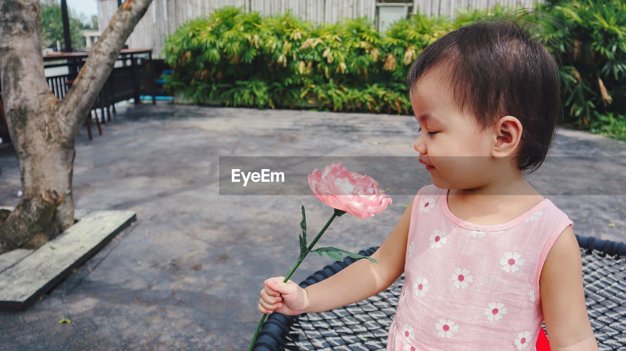 Asian thai little girl looking at flower in outdoor garden.