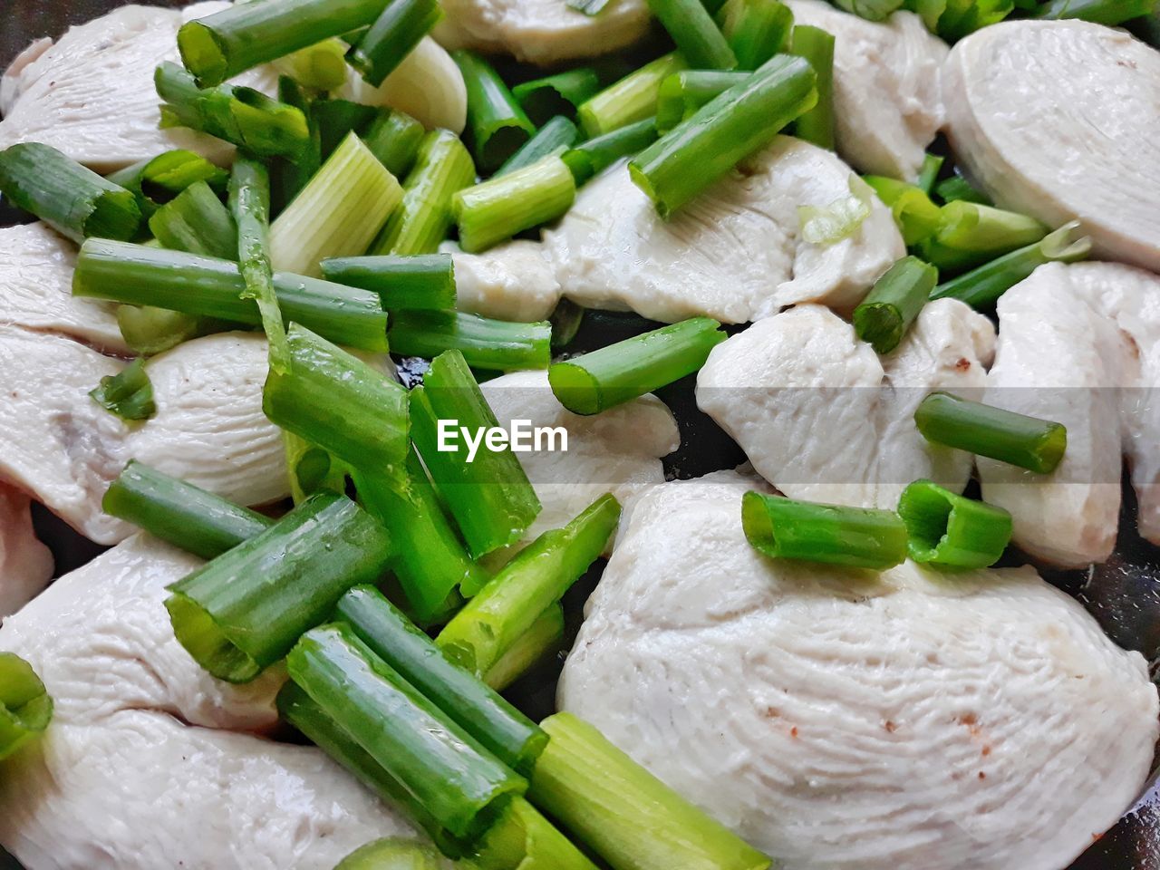 Full frame shot of chopped spring onions
with white chicken fillet. white meat with scallion