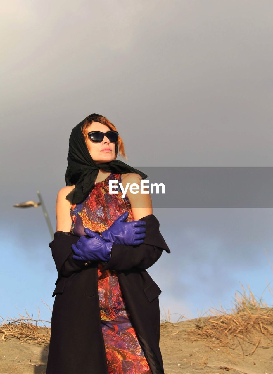 Young woman wearing sunglasses standing on land