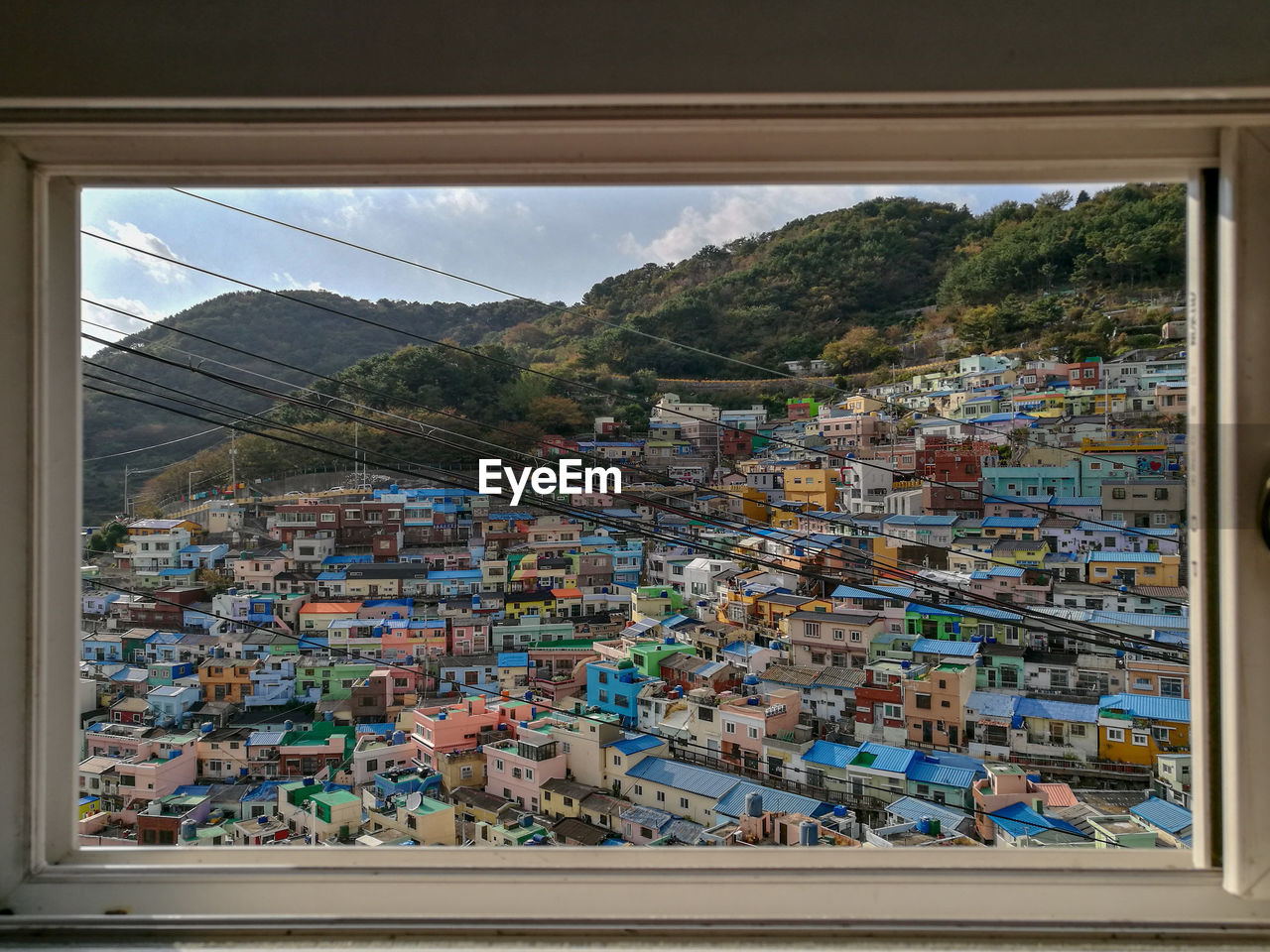 Buildings in city against sky seen through glass window