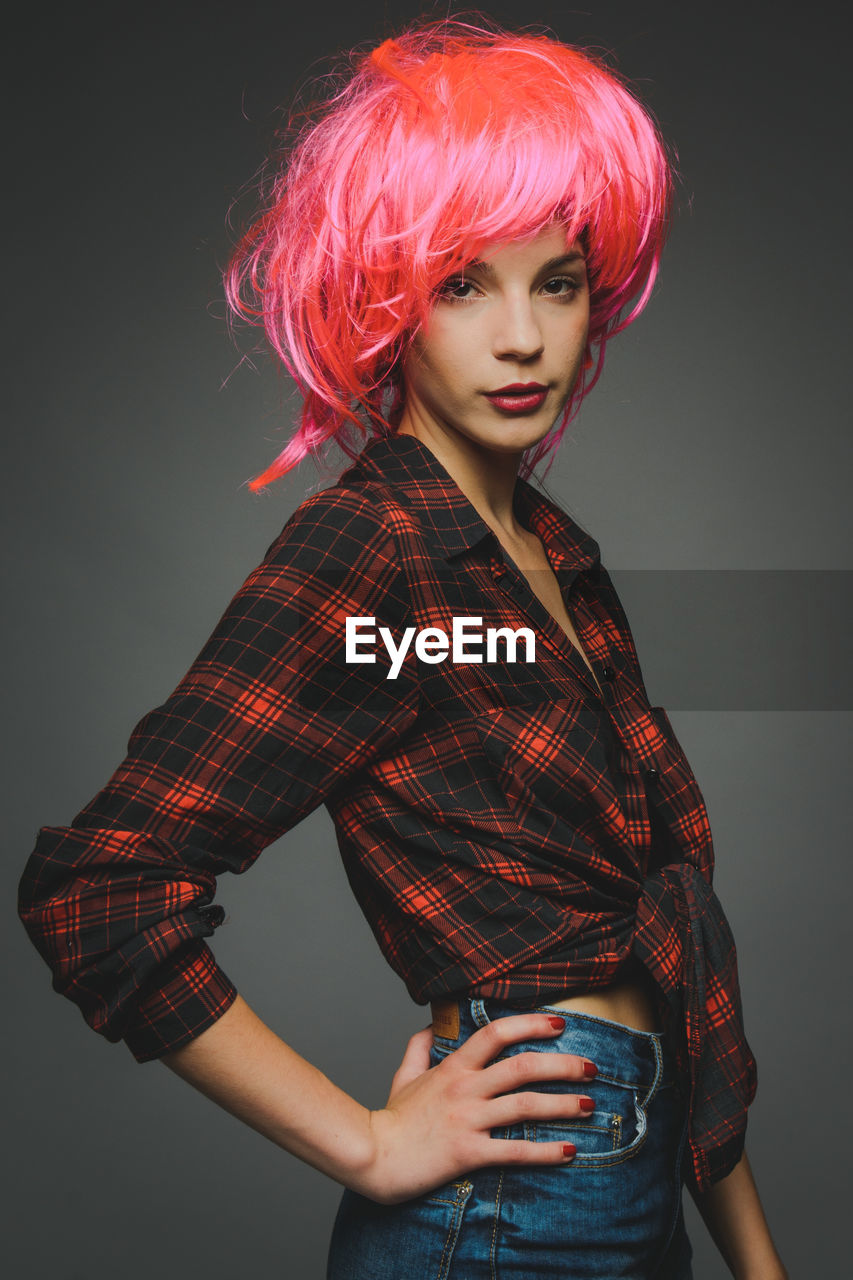 Portrait of beautiful young fashion model with wig against gray background