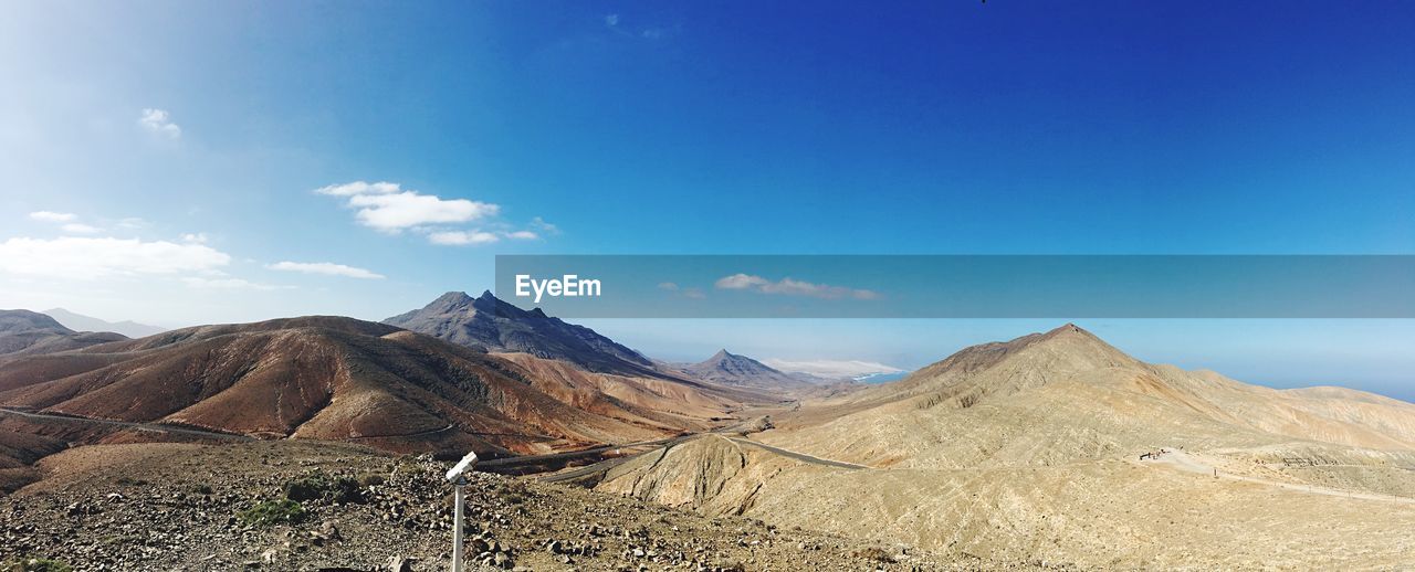 Scenic view of mountains against blue sky