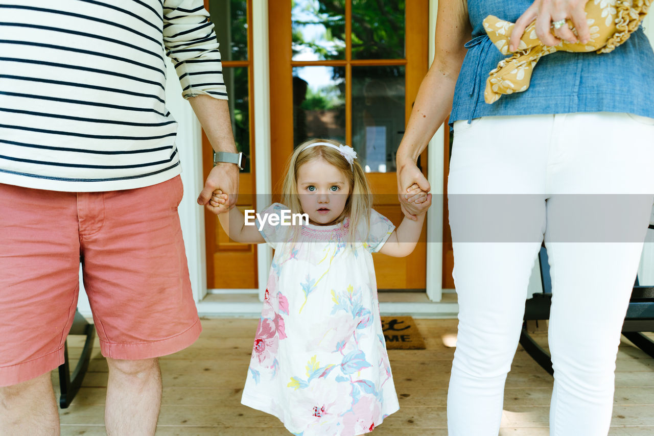 Cropped closeup of a toddler girl holding her parents hands