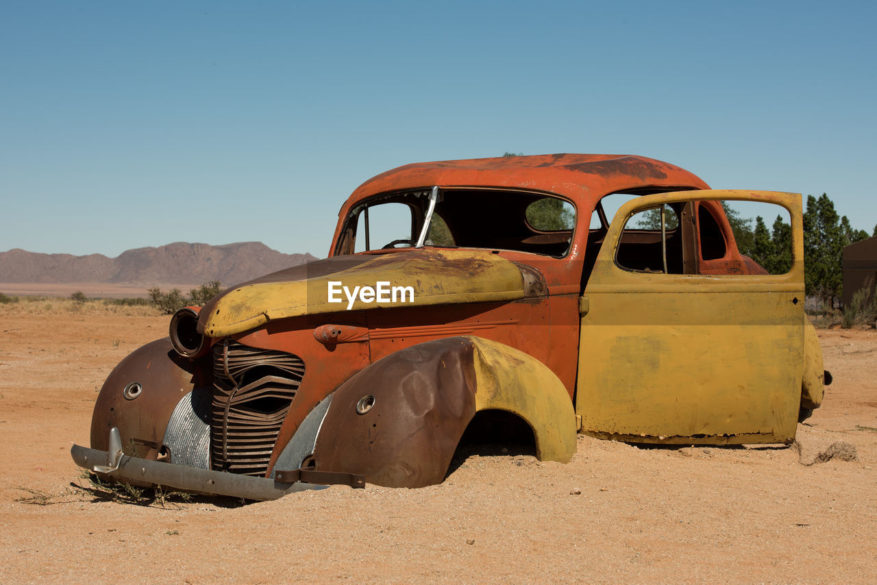 Abandoned vintage car on desert against clear sky