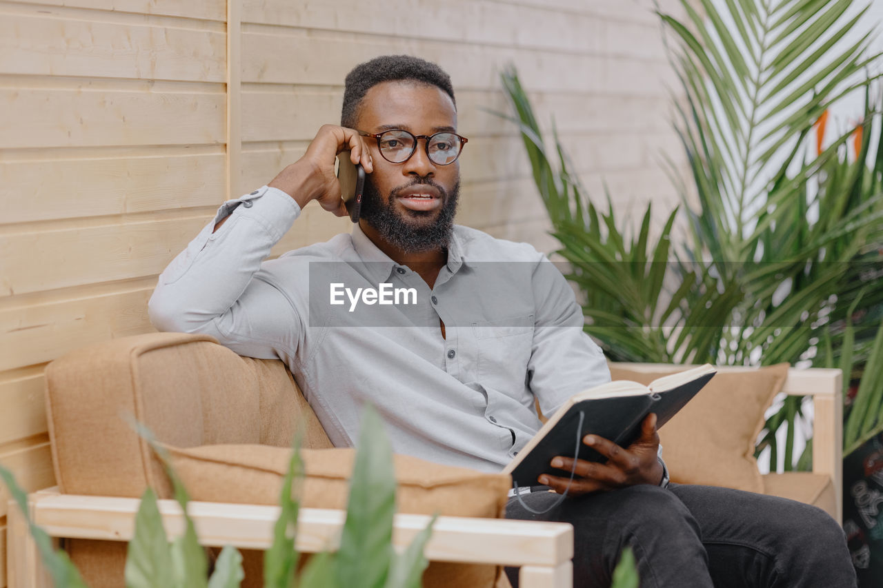 African american in an office or coworking talking on the phone and taking notes in a notebook