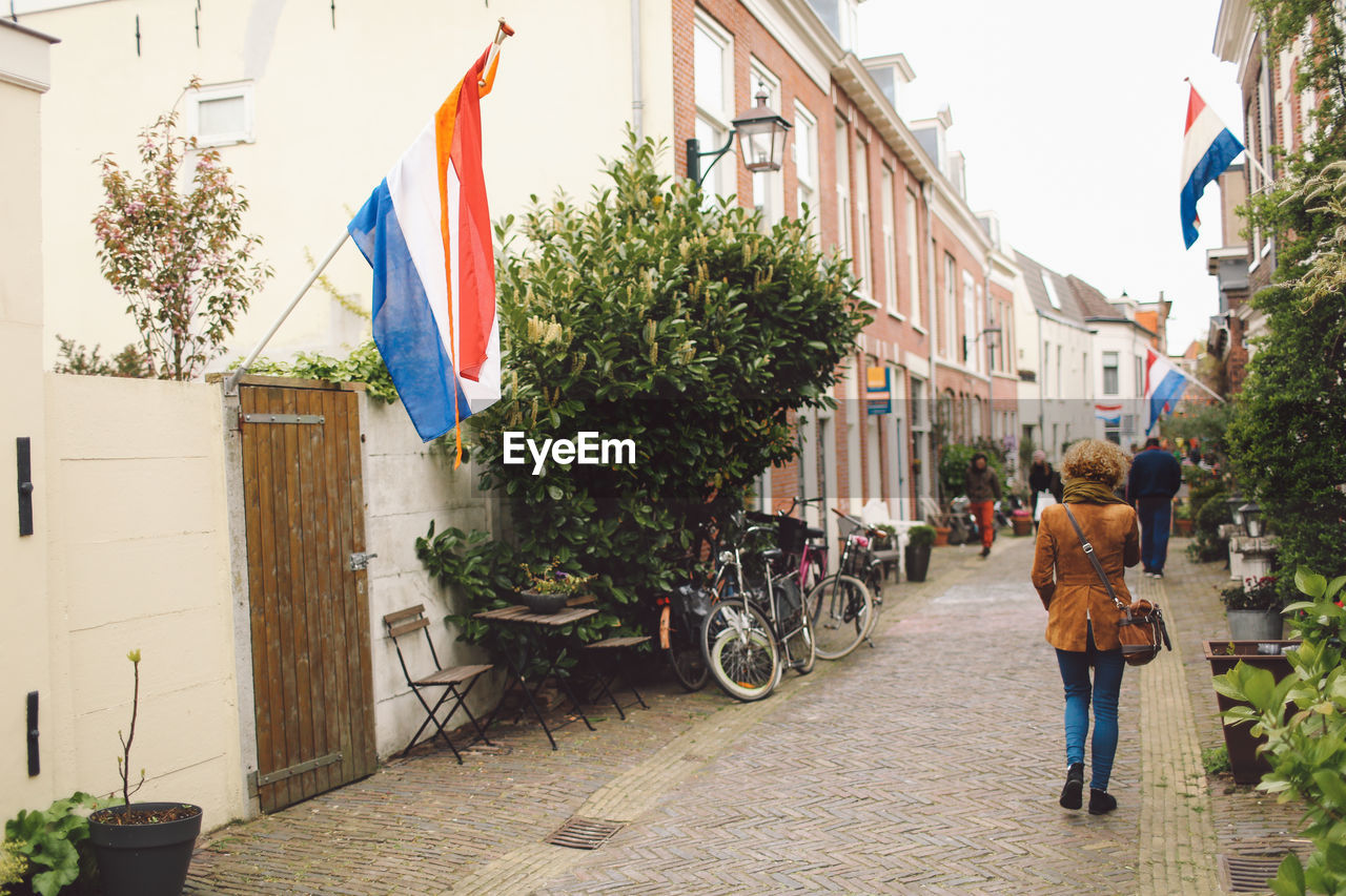 Rear view of woman walking amidst dutch flags on buildings