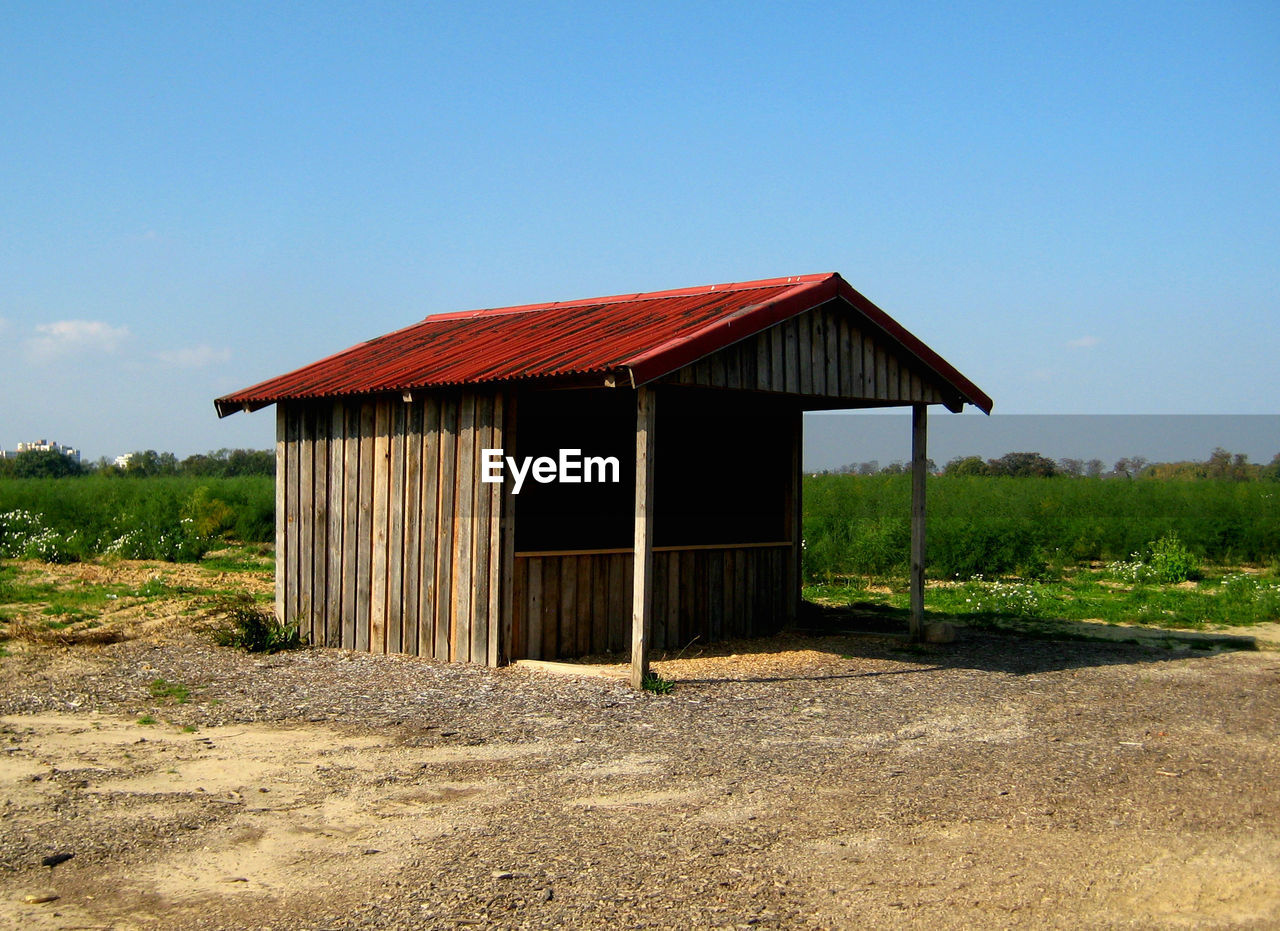 Log cabin on field against clear blue sky