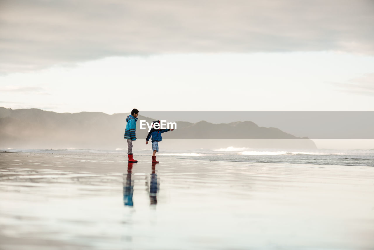 Brothers at beach in new zealand on winter day