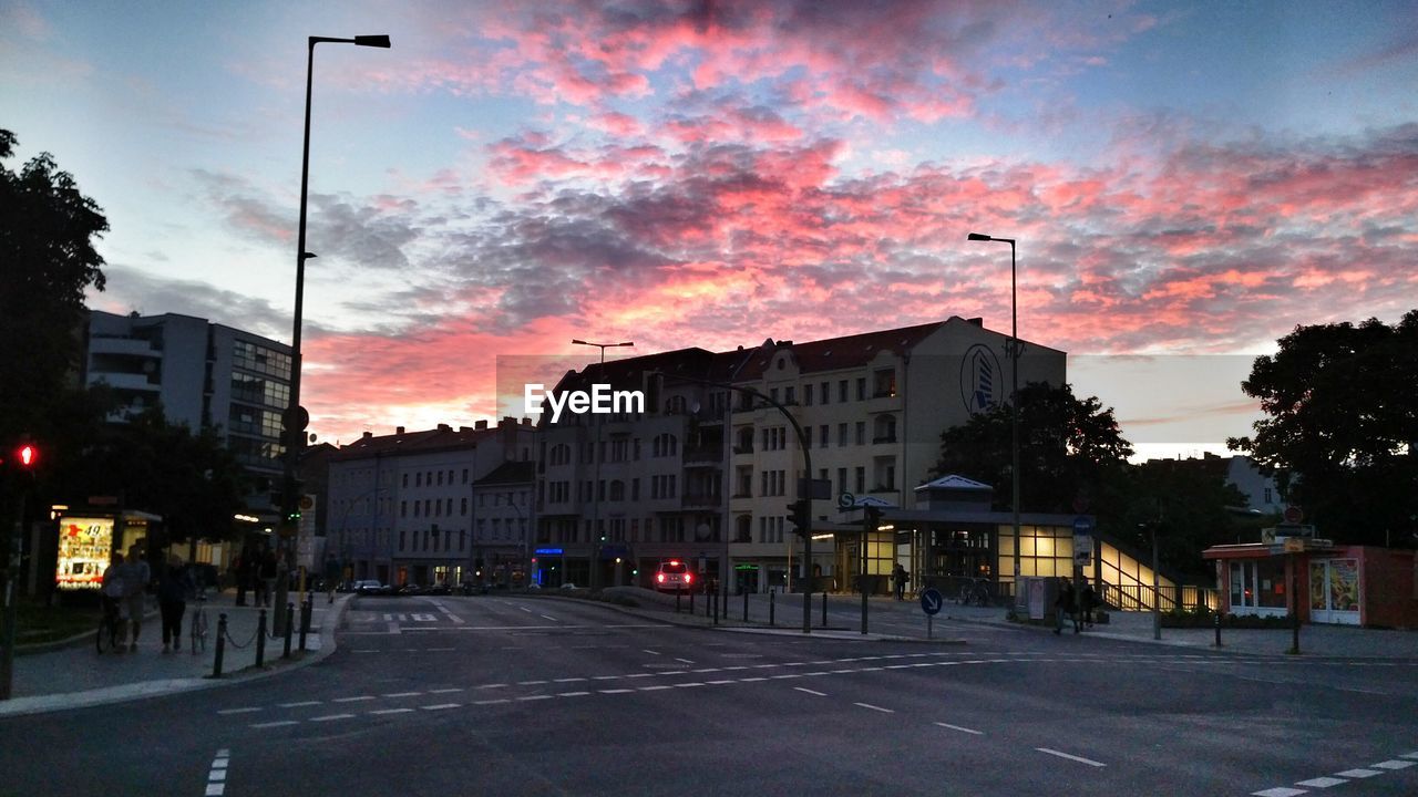 VIEW OF CITY STREET AGAINST CLOUDY SKY AT DUSK