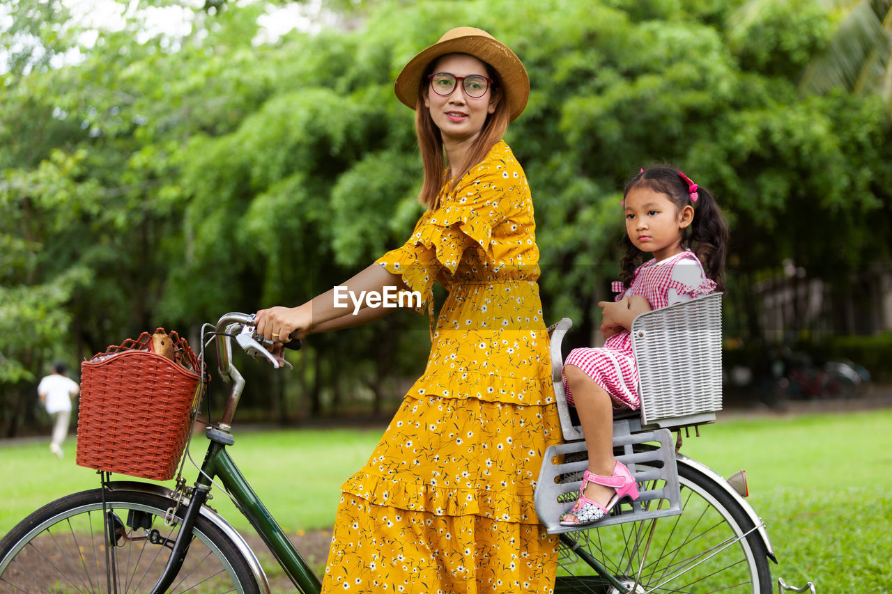 PORTRAIT OF SMILING WOMAN RIDING BICYCLE ON PLANTS