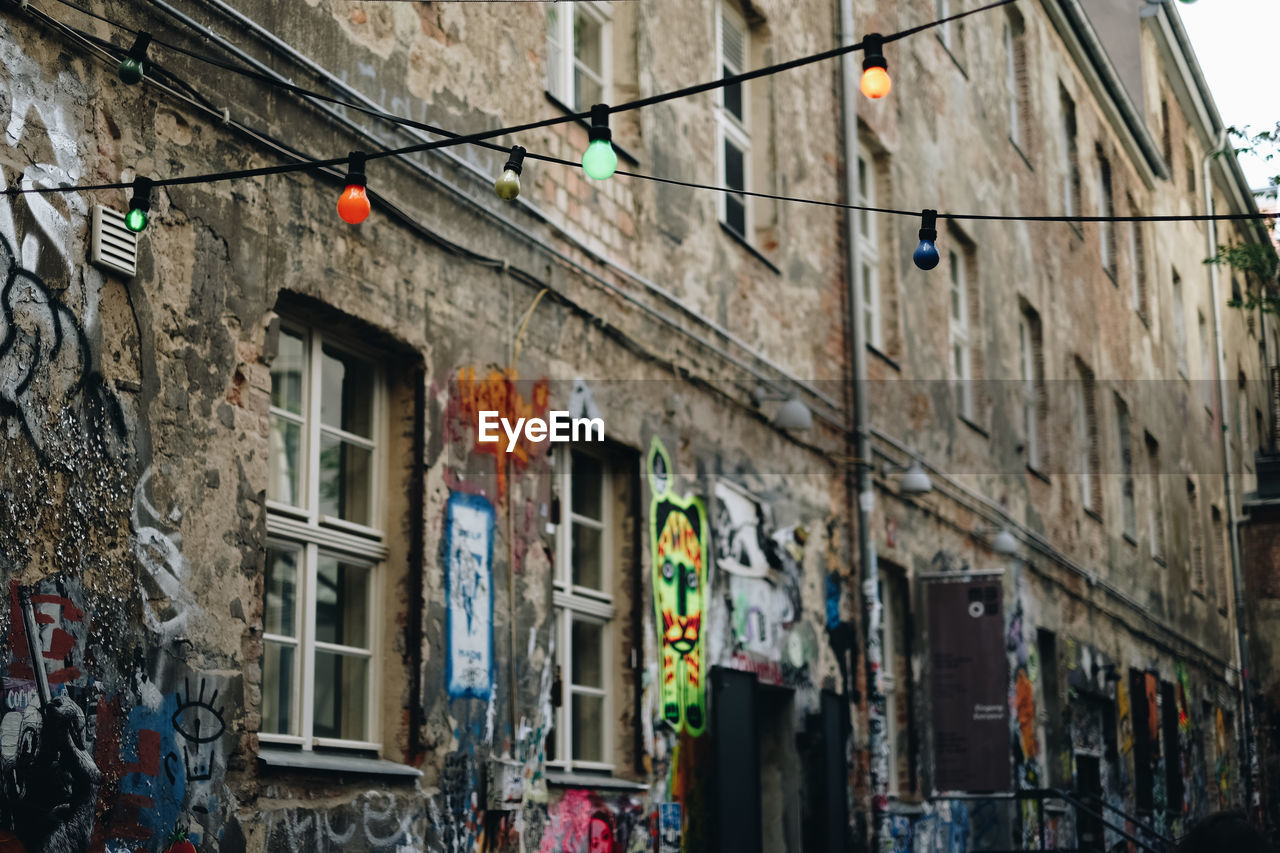 Low angle view of colorful bulbs hanging from string against building