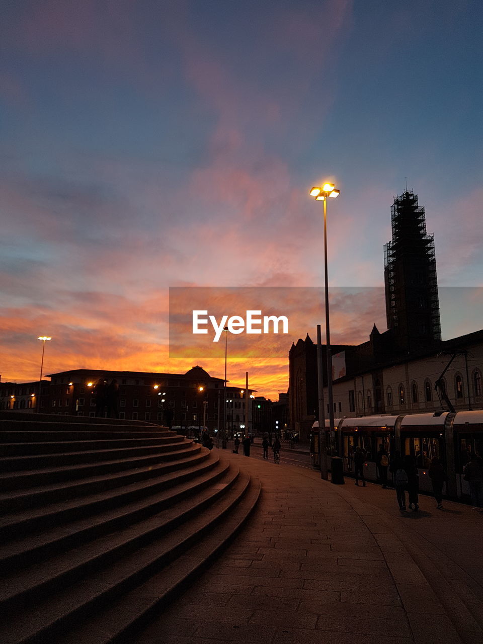 Street amidst buildings against sky at sunset