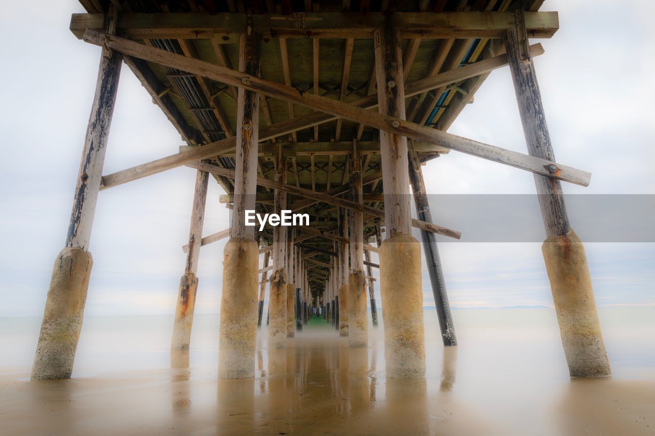 Low angle view of pier over sea against sky