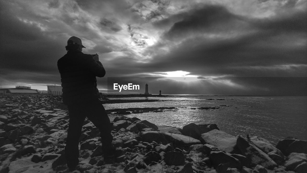 SILHOUETTE WOMAN STANDING ON BEACH AGAINST SKY