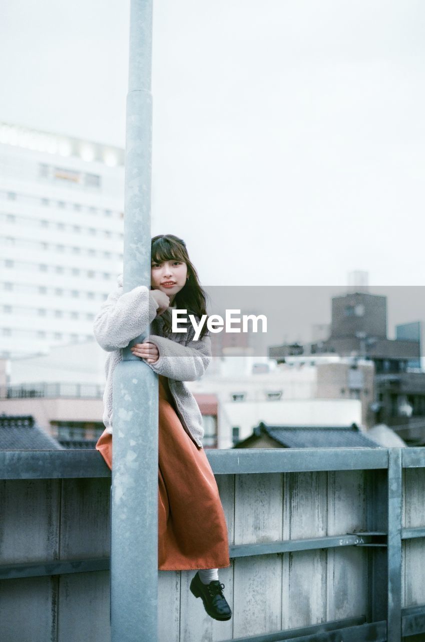 PORTRAIT OF WOMAN STANDING AGAINST CITY