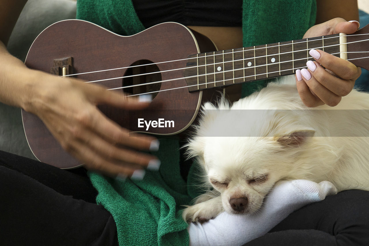 Woman playing ukulele. dog sleeping near. digital detox, simple pleasures, mental health concept.