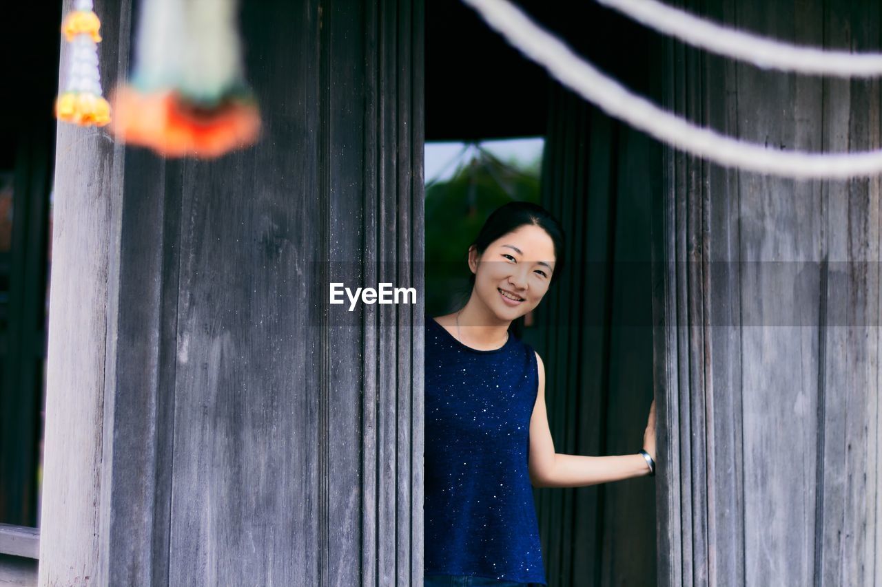 Portrait of smiling young woman standing at doorway