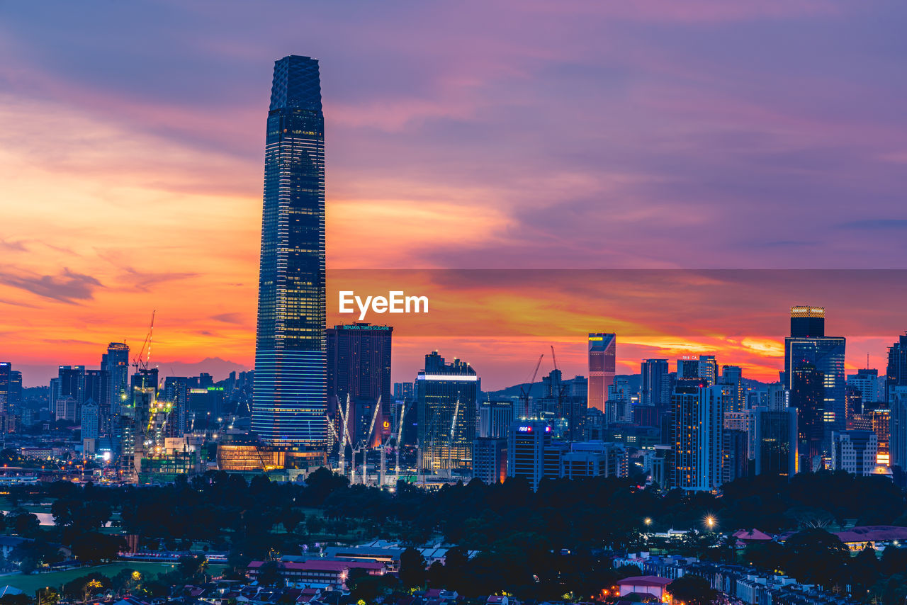 ILLUMINATED MODERN BUILDINGS AGAINST SKY DURING SUNSET