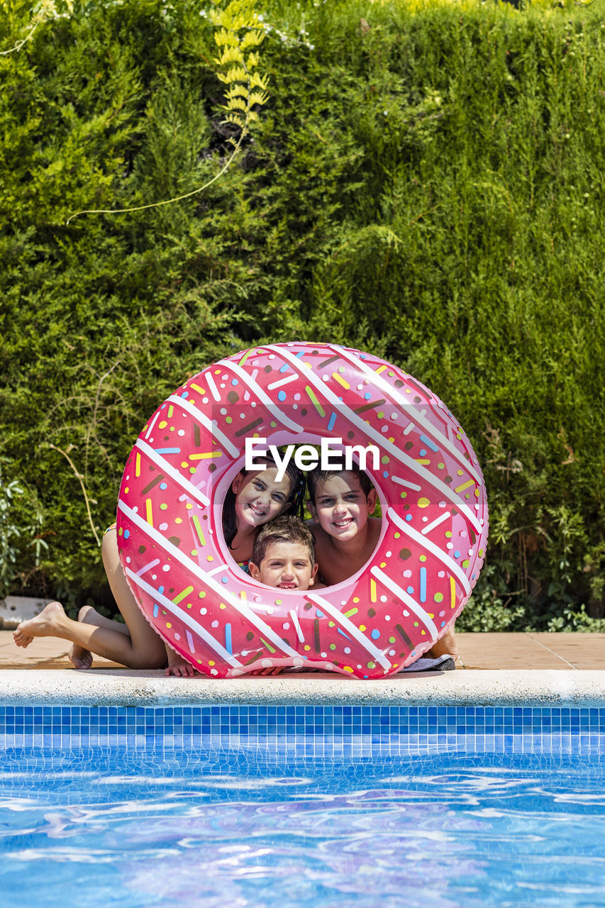 Three kids posing on a hole of a rubber ring