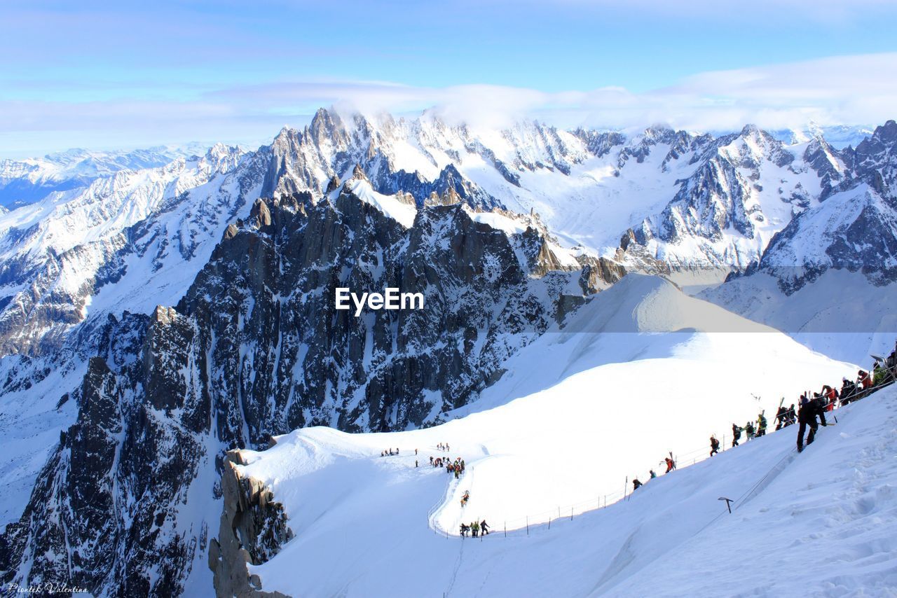 Scenic view of snow covered mountains against cloudy sky