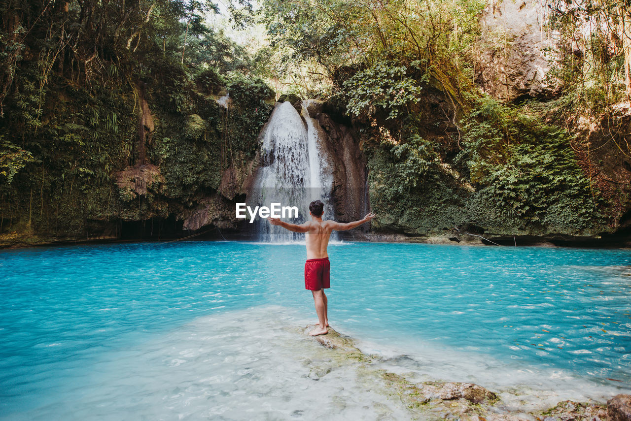 Man looking waterfall in forest