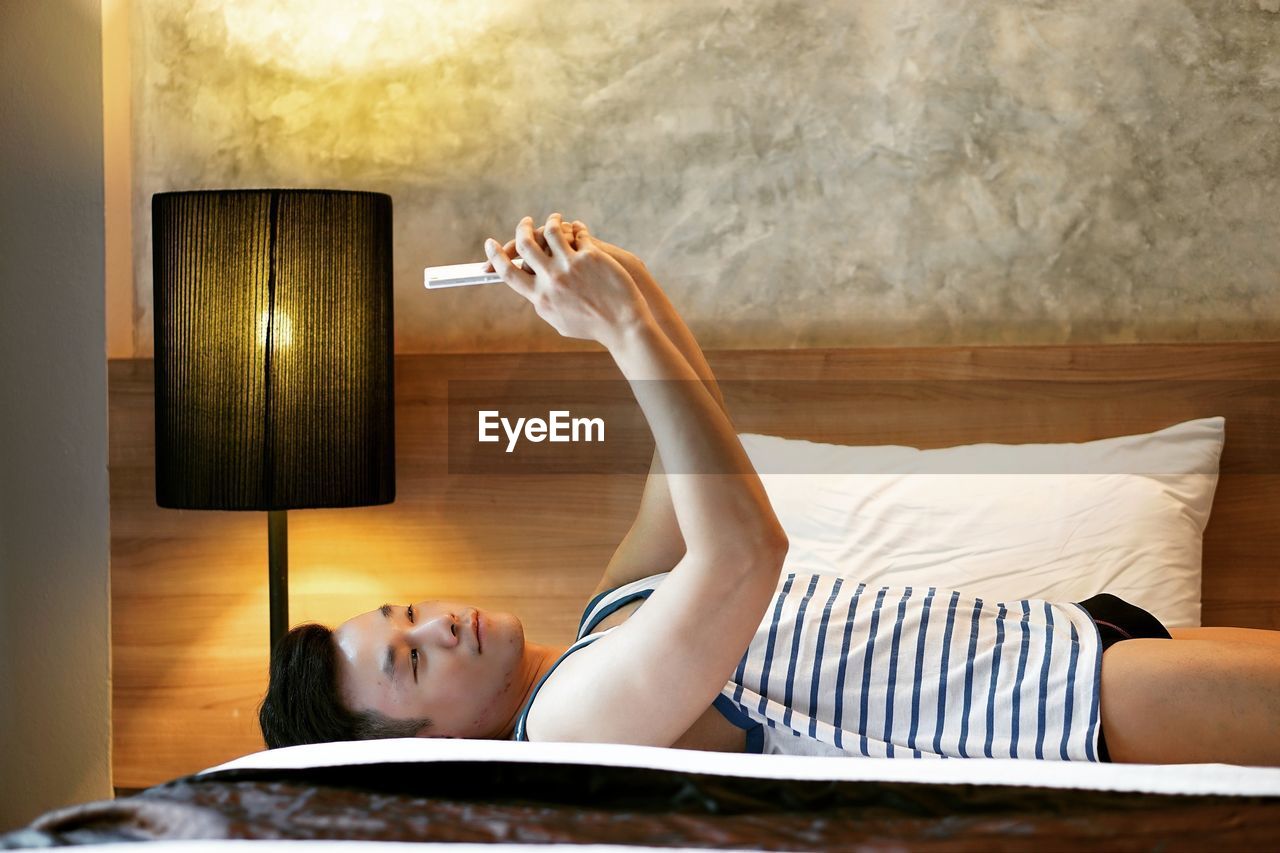 Man taking selfie while lying on bed