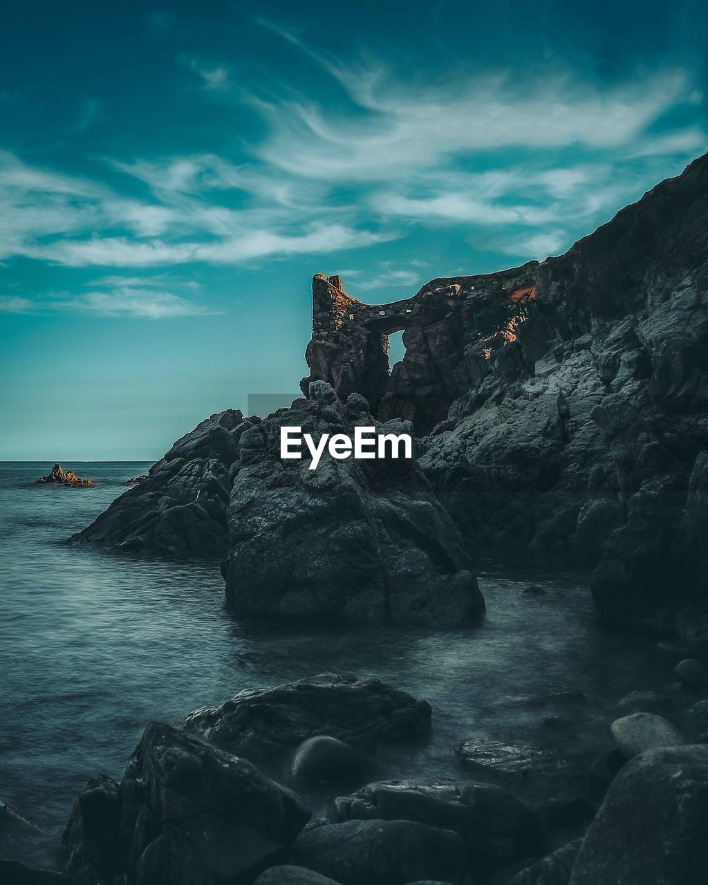 ROCK FORMATION ON SEA AGAINST SKY