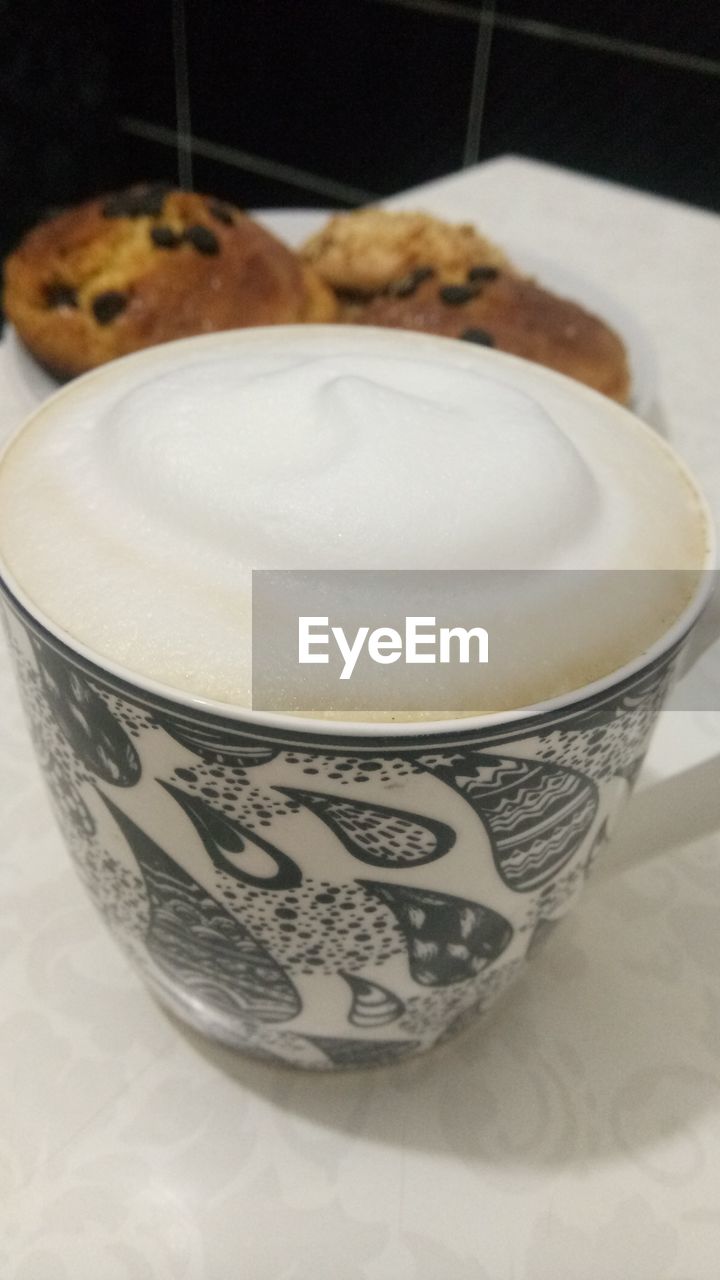 CLOSE-UP OF COFFEE CUP WITH SPOON ON TABLE