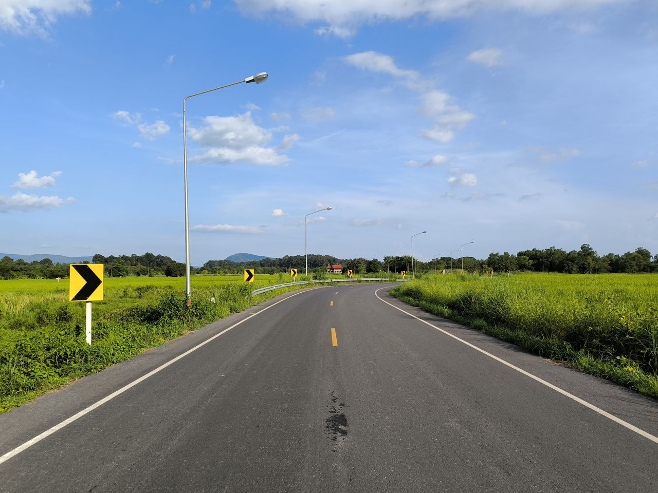 road, transportation, sky, highway, cloud, nature, lane, street, the way forward, landscape, environment, freeway, symbol, sign, asphalt, plant, no people, diminishing perspective, road marking, land, vanishing point, grass, day, marking, city, travel, rural scene, outdoors, scenics - nature, street light, tree, beauty in nature, horizon, tranquility, road surface, infrastructure, mode of transportation, country road, blue, sunlight, travel destinations, field, road sign, tranquil scene