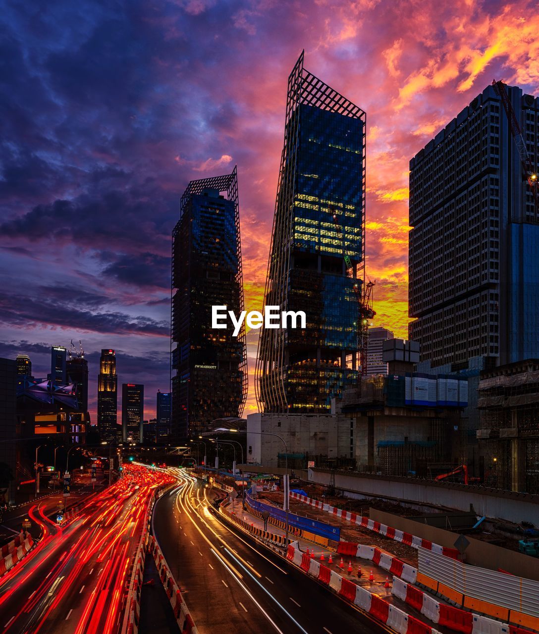 Light trails on illuminated buildings in city against sky during sunset