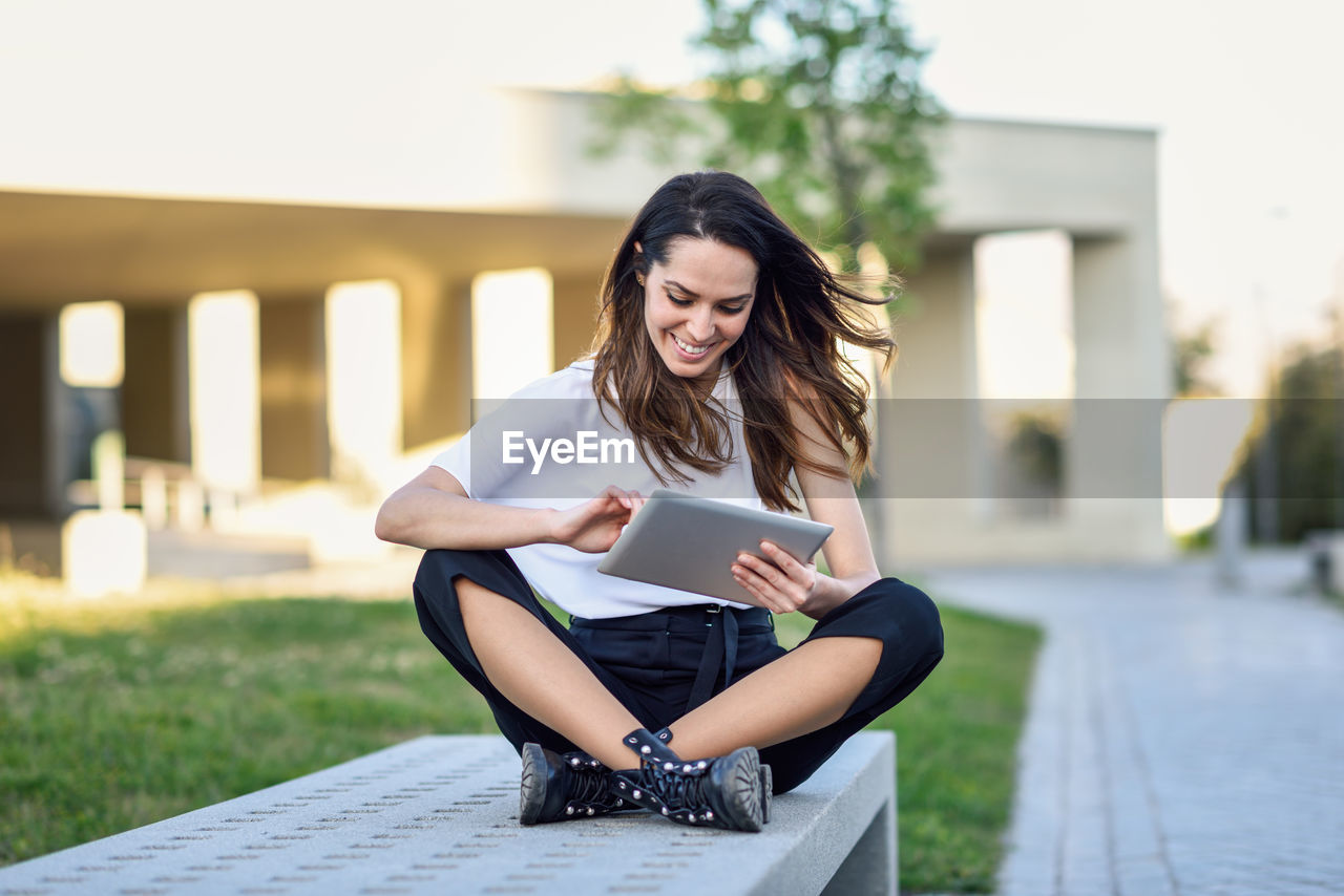 Smiling businesswoman using digital tablet in city