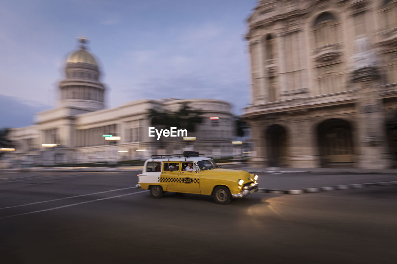 CAR ON STREET BY BUILDINGS AGAINST SKY