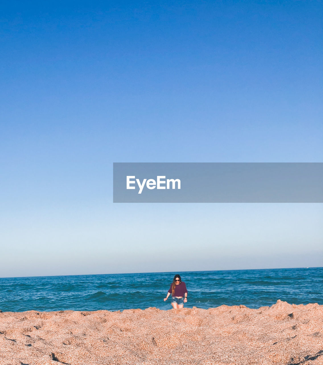 Woman on beach against clear blue sky