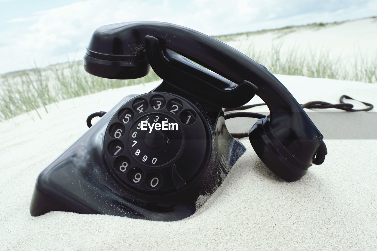 Close-up of retro telephone on sand
