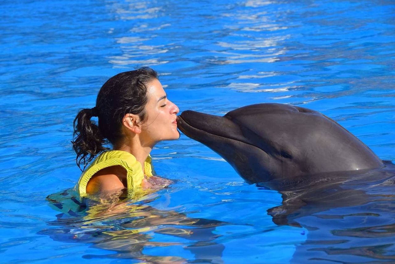 Young woman kissing dolphin