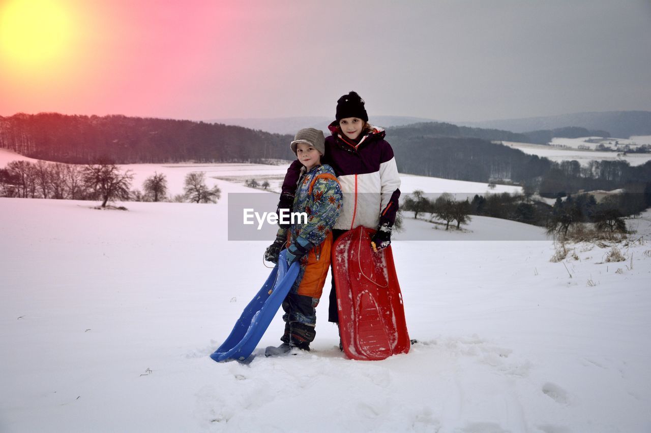 FULL LENGTH PORTRAIT OF WOMAN STANDING ON SNOW COVERED LANDSCAPE