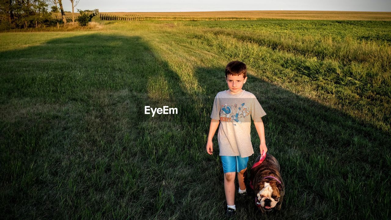 Full length of boy standing with dog on field