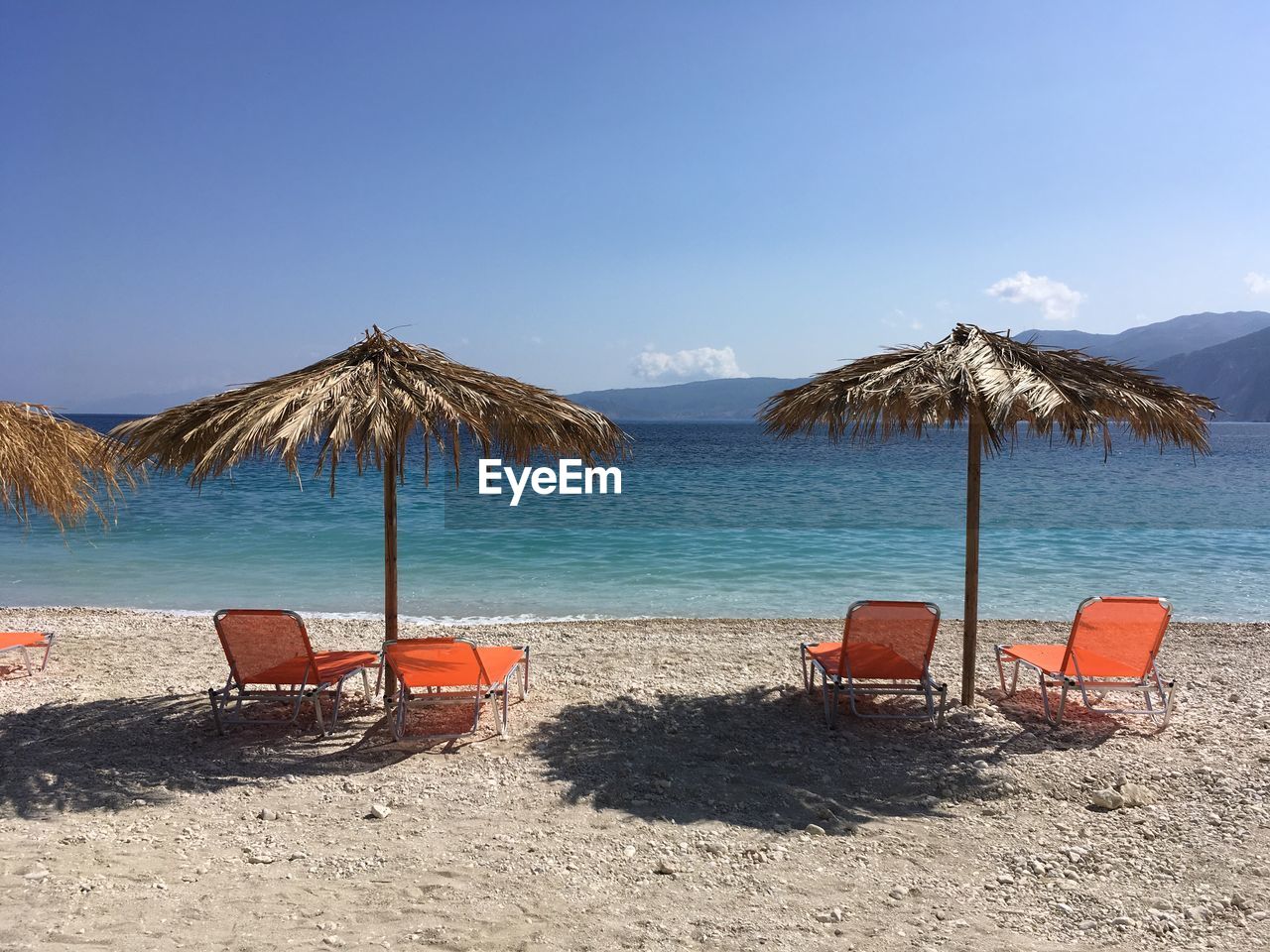 Chairs on beach by sea against sky