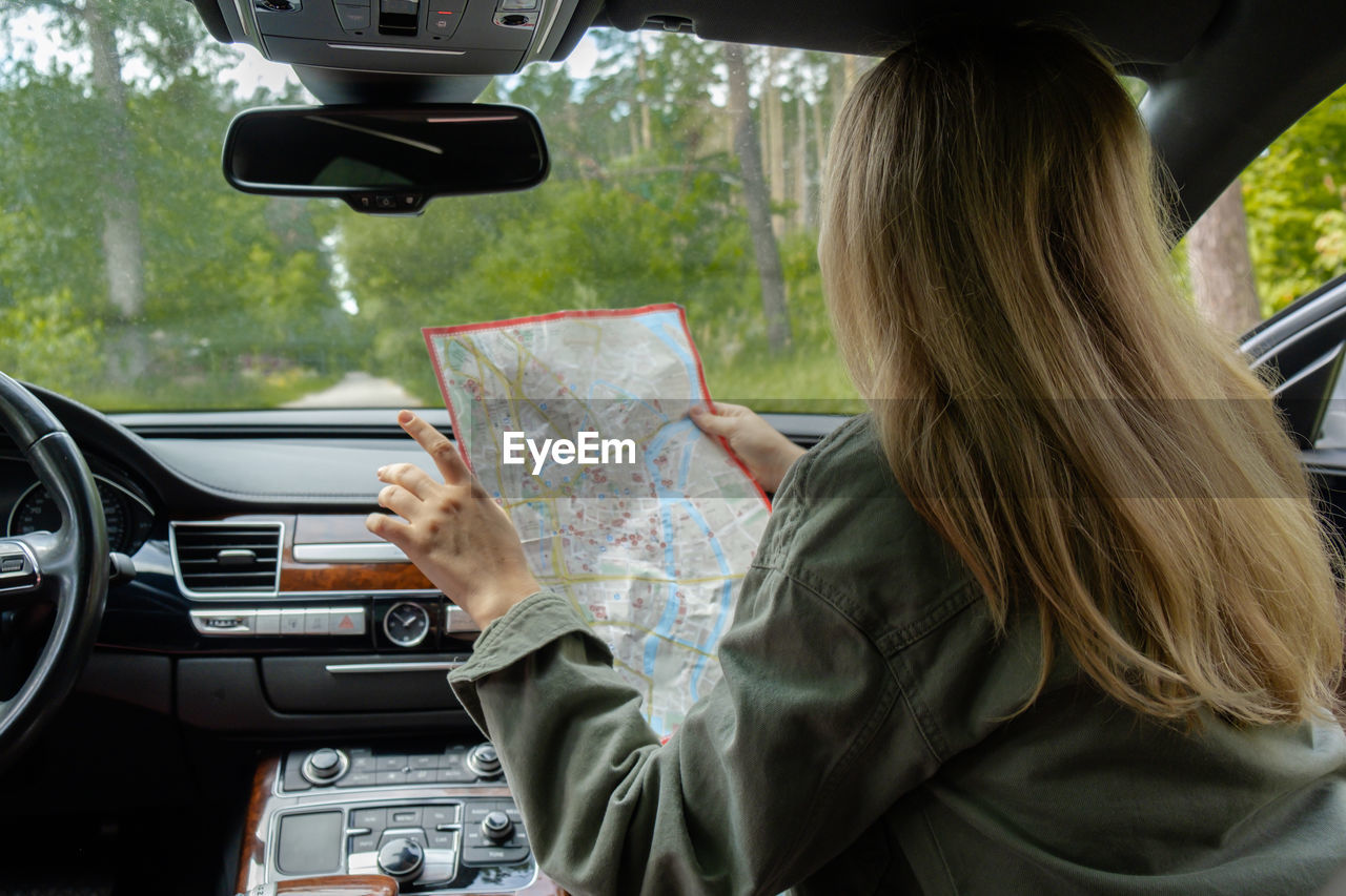 midsection of woman using mobile phone while sitting in car