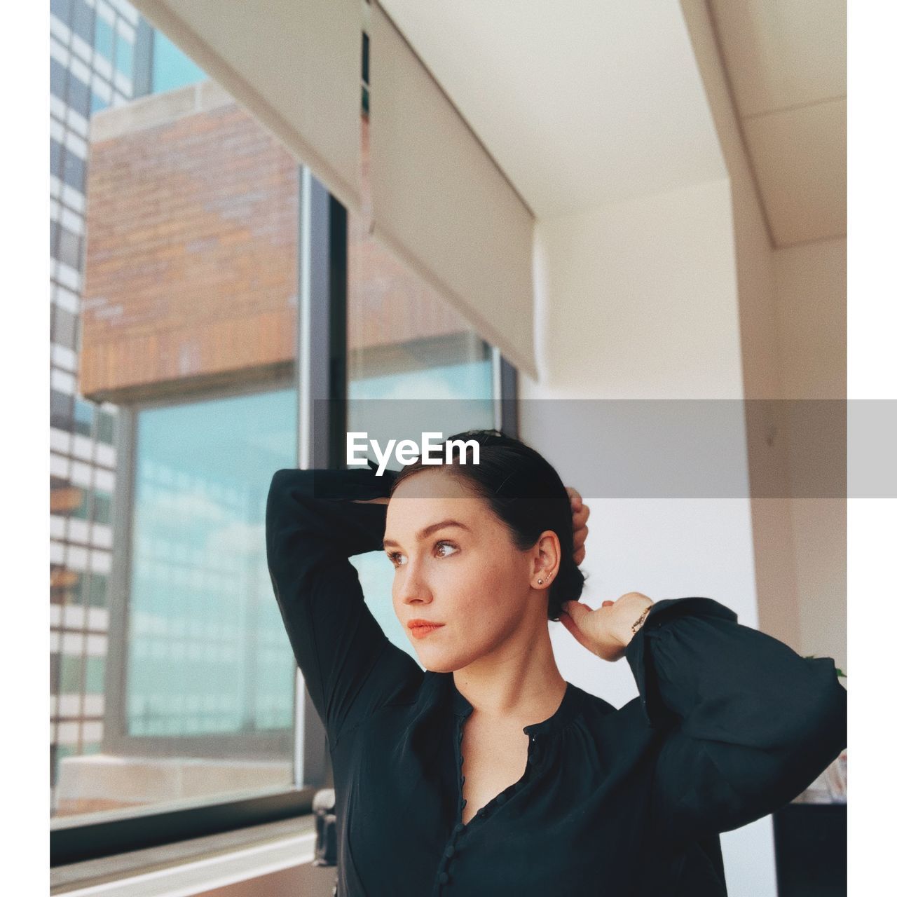 Young woman with hand in hair looking through window