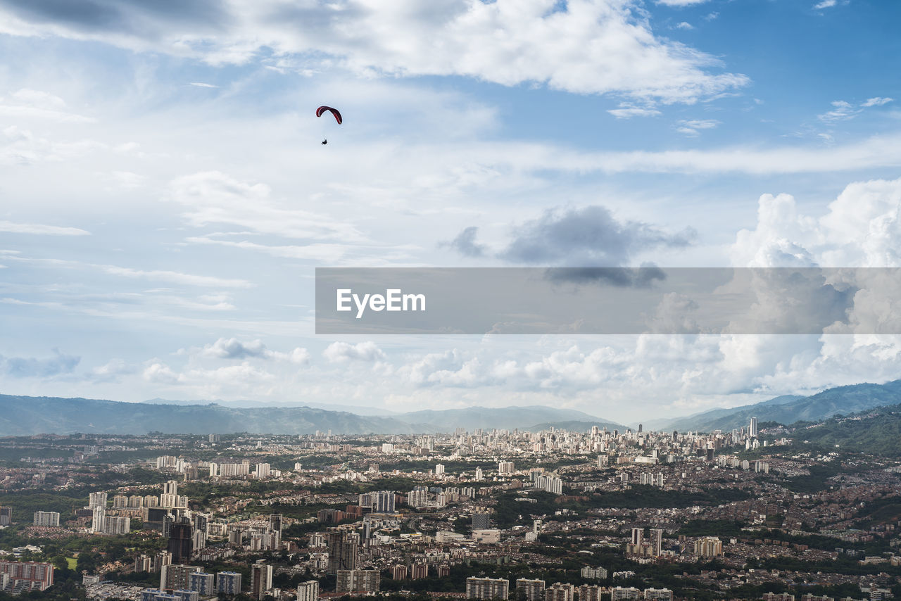 Aerial view of townscape against sky with paraglider