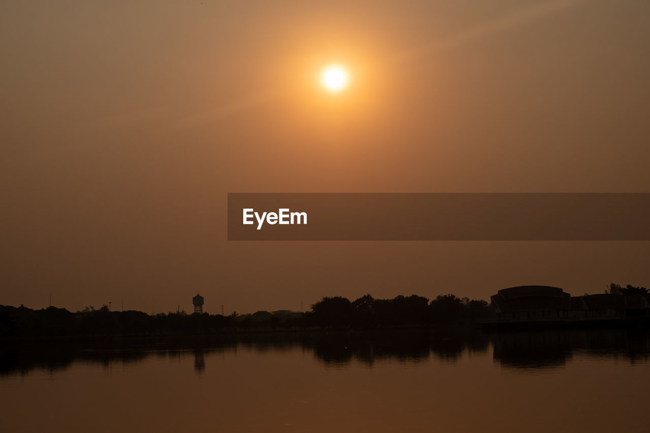 SCENIC VIEW OF LAKE AGAINST SKY AT SUNSET