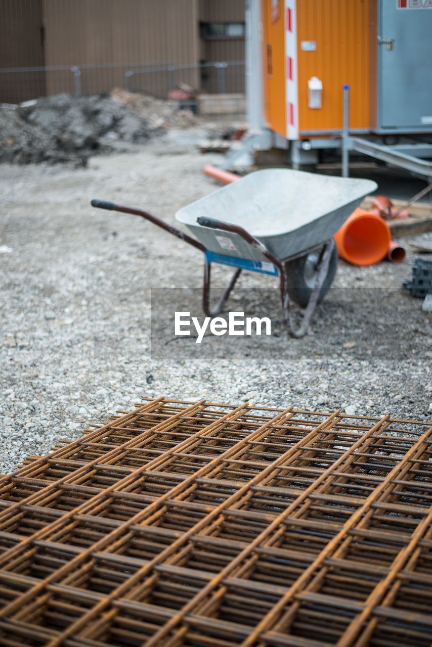 High angle view of metal grates by wheelbarrow at construction site