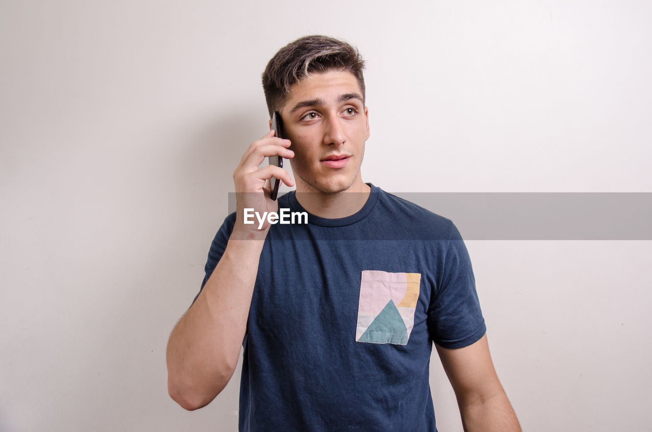 PORTRAIT OF YOUNG MAN USING SMART PHONE