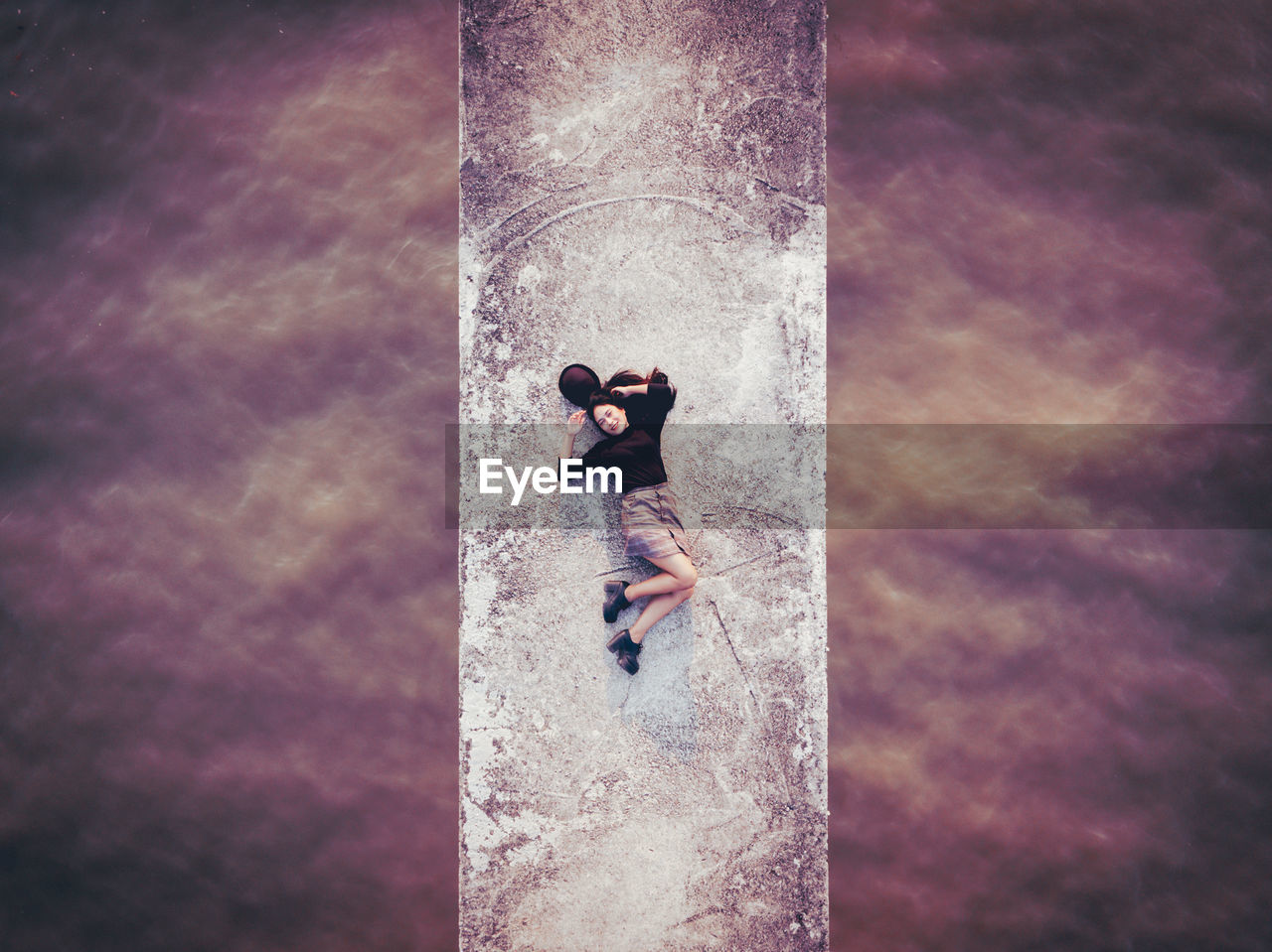 Aerial view of woman lying on bridge over sea